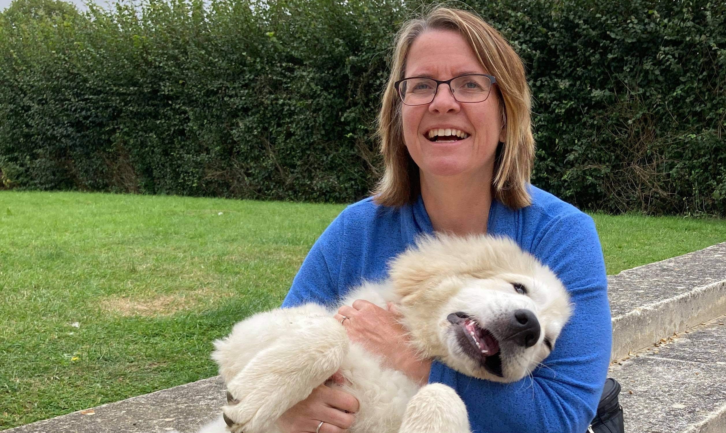 Clair and dog having a cuddle sat on a wall outside in a garden